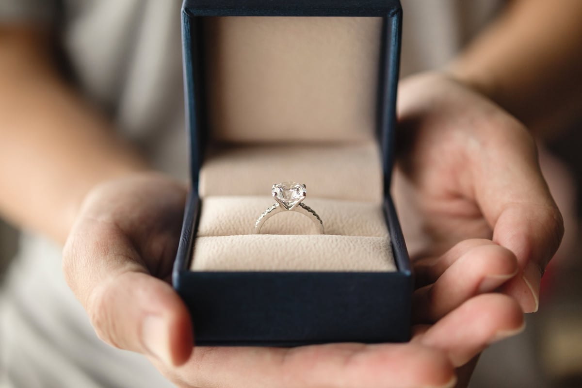 Hands holding diamond ring in jewelry box
