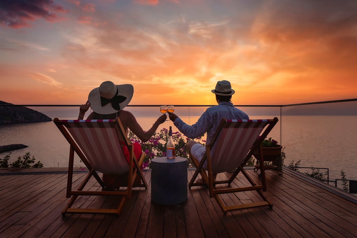 Couple enjoying sunset over Mediterranean sea with wine