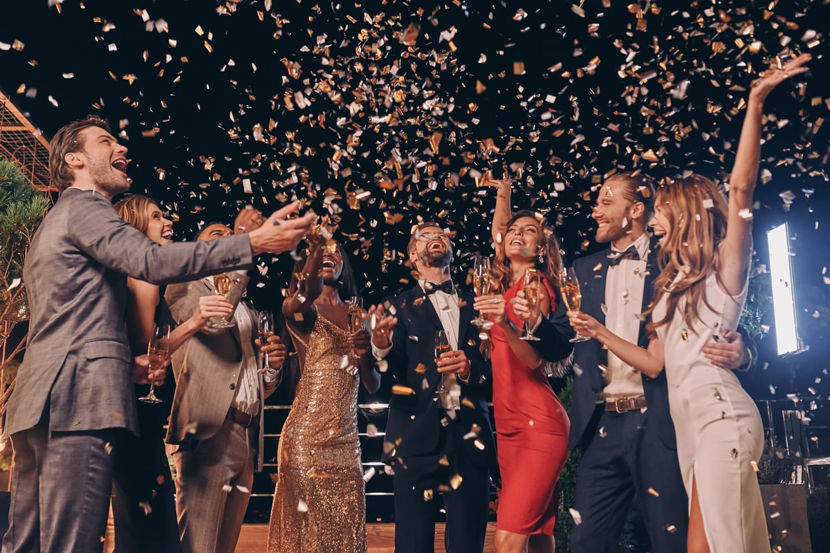 Group of beautiful people in formalwear having fun at a celebration with confetti