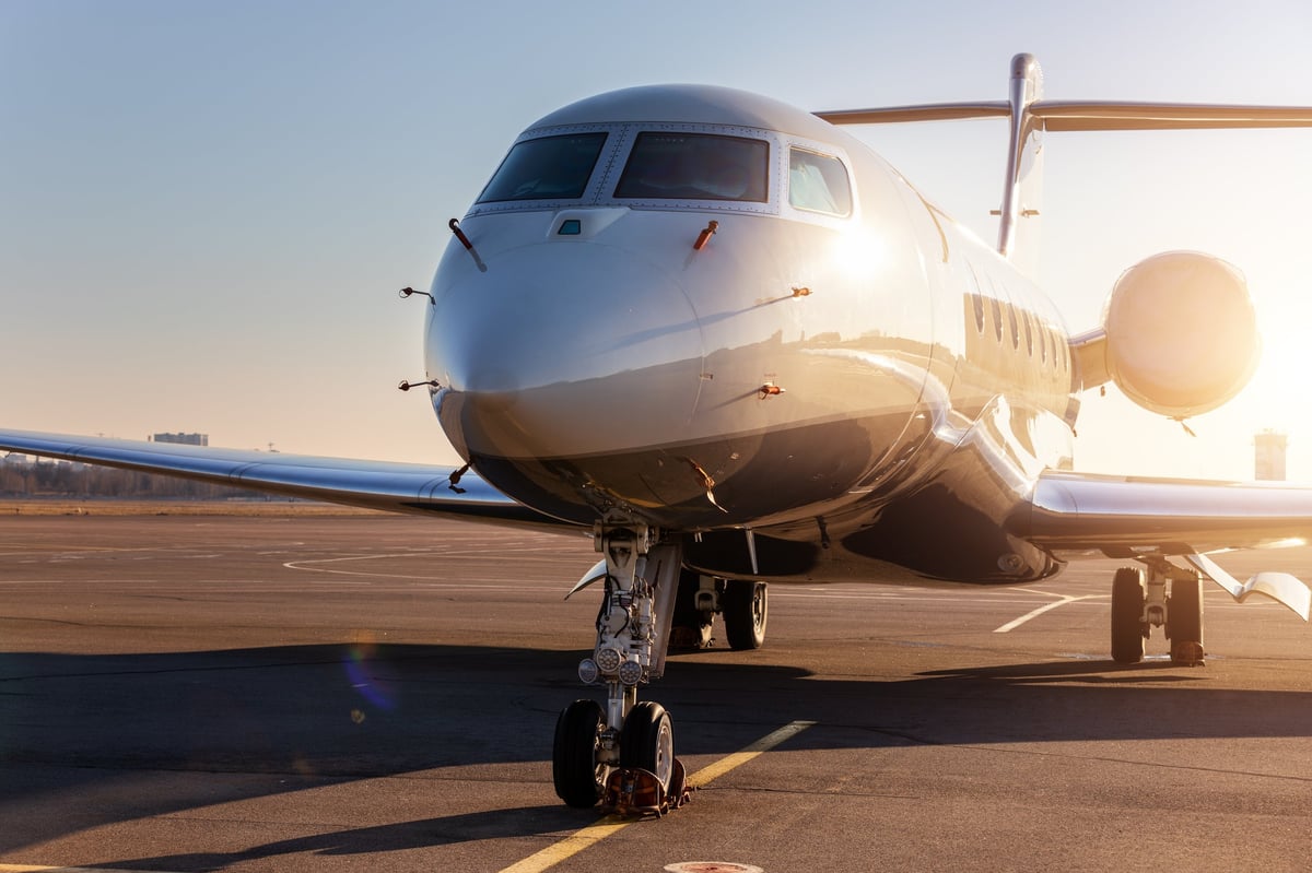 Scenic front view modern luxury expensive private jet plane parked airport taxiway hangar at sunset