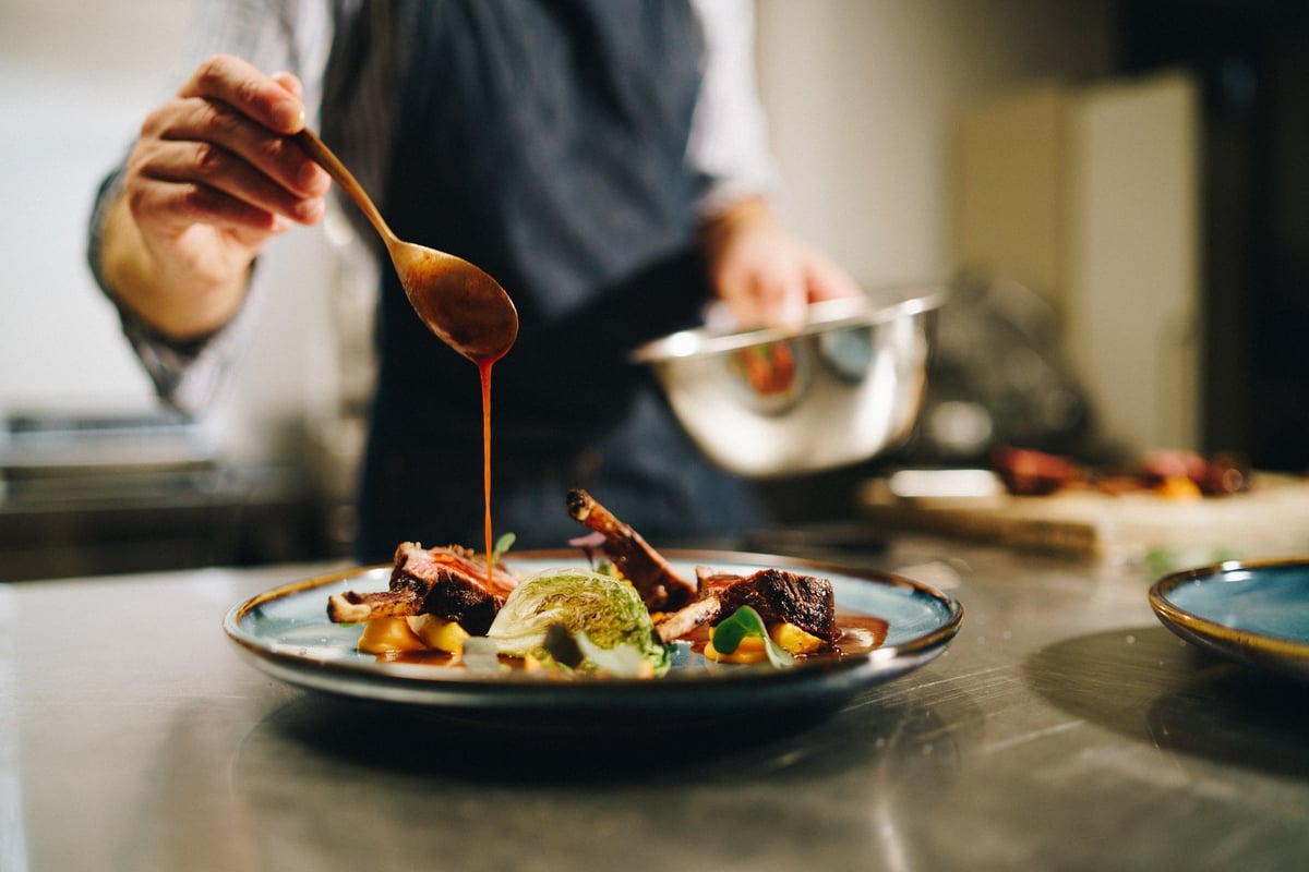 Chef pouring sauce on dish