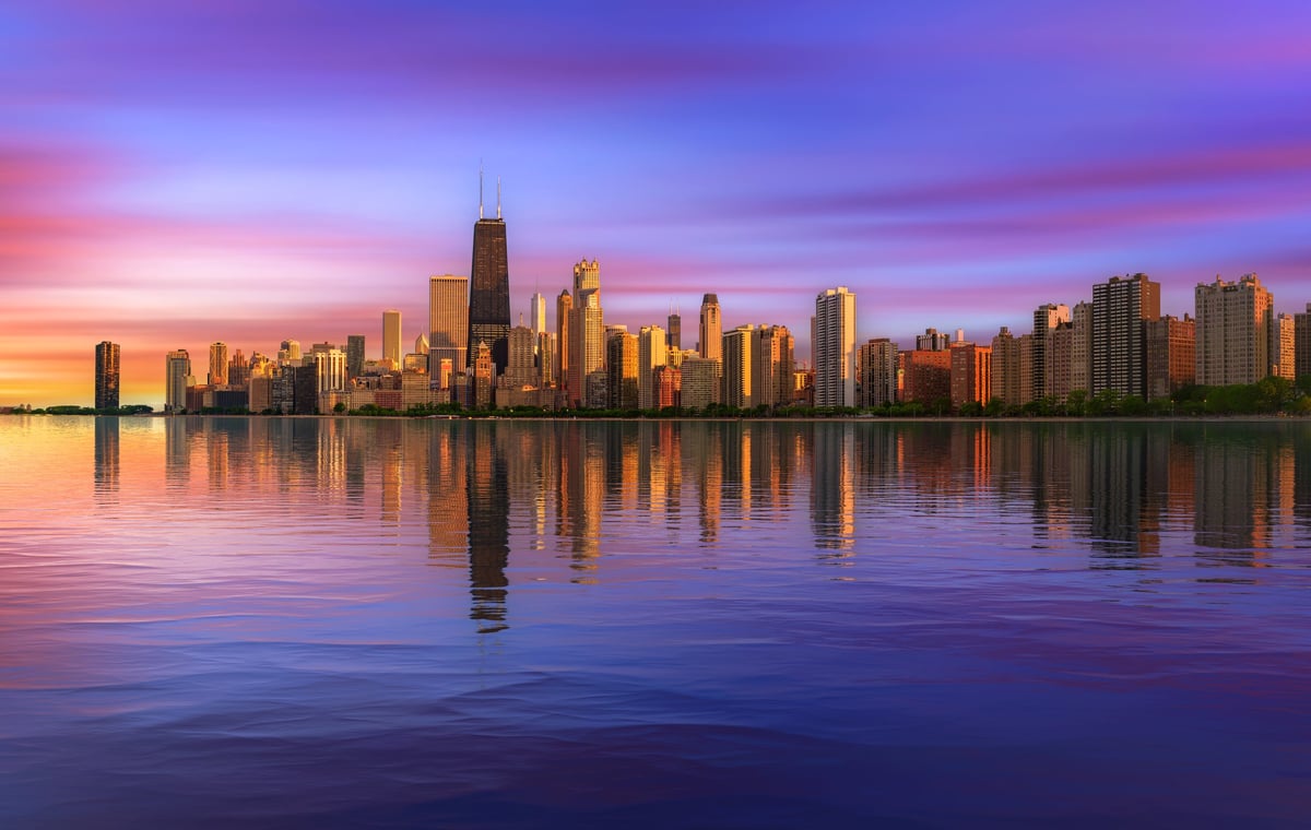 Colorful sunset above Chicago skyline across Lake Michigan with reflection in water
