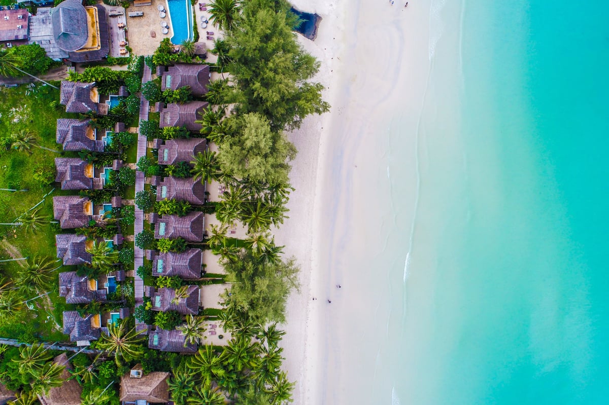 Sea beach with resort resident and coconut palm tree aerial view