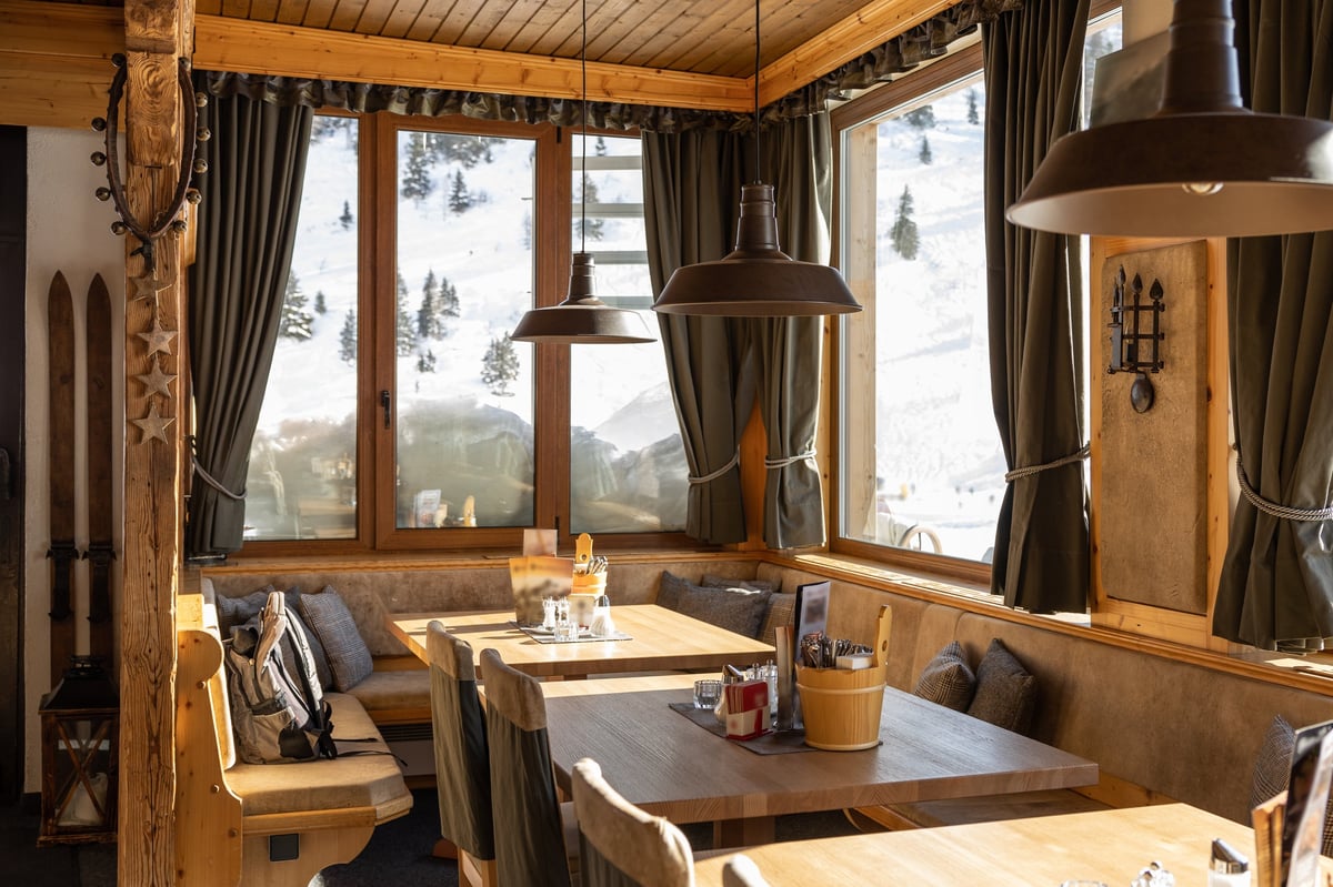Illuminated by bright morning sunlight, the hall of the Alpine restaurant with panoramic windows and snow on the windowsills, Austria. High quality photo