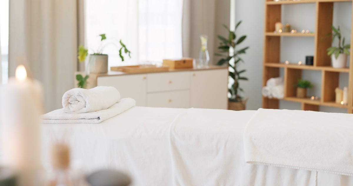 Spa, massage bed and background with candles and empty room for health, wellness and treatment