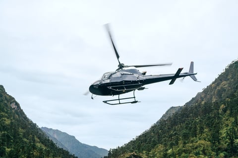 Civil helicopter flying in high altitude with dramatic mountain backdrop