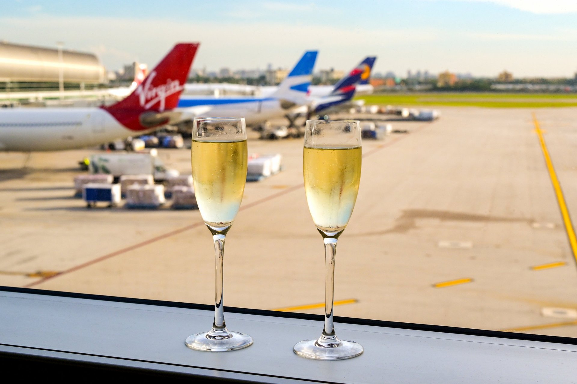 Two champagne flutes on windowsill of luxury airport lounge overlooking runway