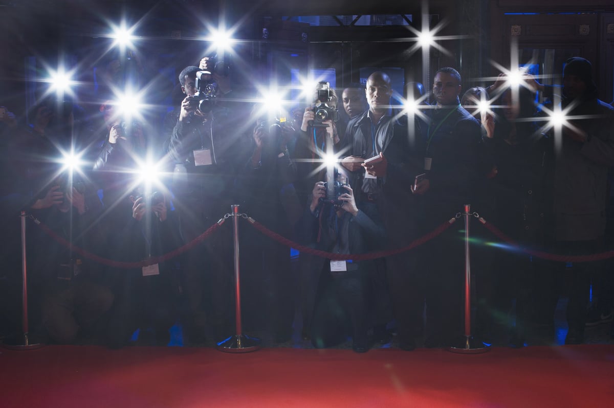 Photographers with flashing cameras lined up behind a red rope on a red carpet event at Cannes film festival