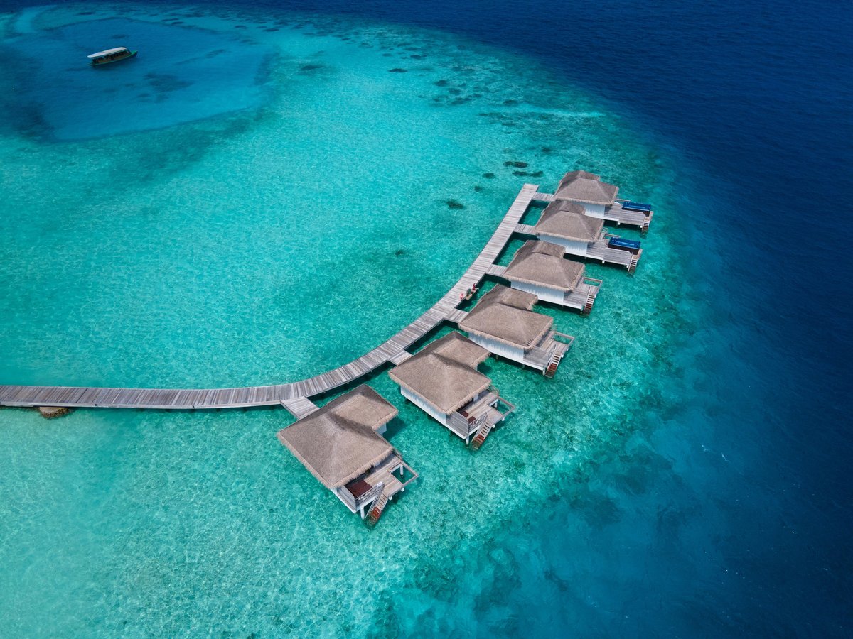 hotel in Maldives aerial view, wooden bungalows over turquoise water lagoon