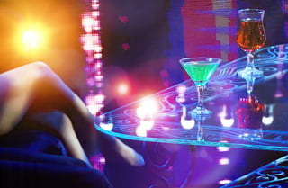 Close-up shot in dimly lit nightclub with cocktails under neon lights