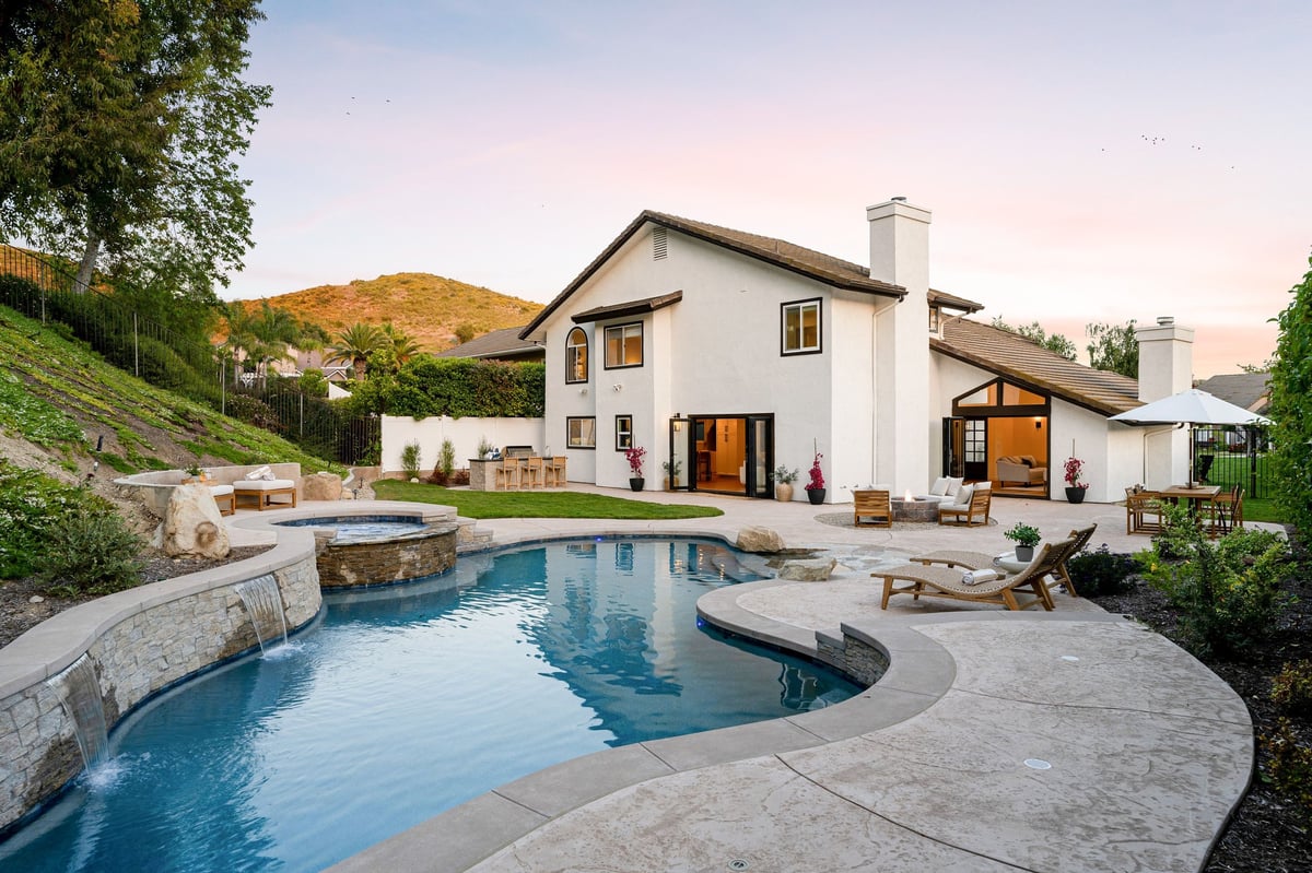 Luxury backyard with pool and hot tub at modern house during sunset