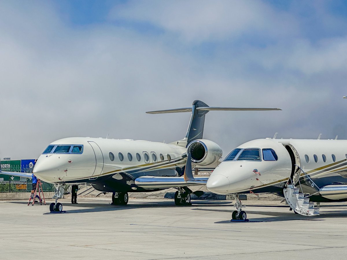 2 White Blue and Gold Private Jets Parked on a Runway