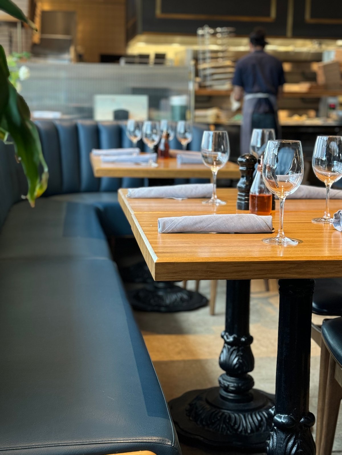 Interior of nice restaurant with empty set tables with blue booth seats and empty wine glasses