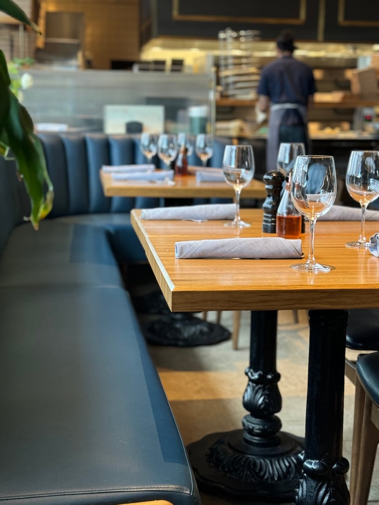 Interior of nice restaurant with empty set tables with black iron stands, blue booth seats