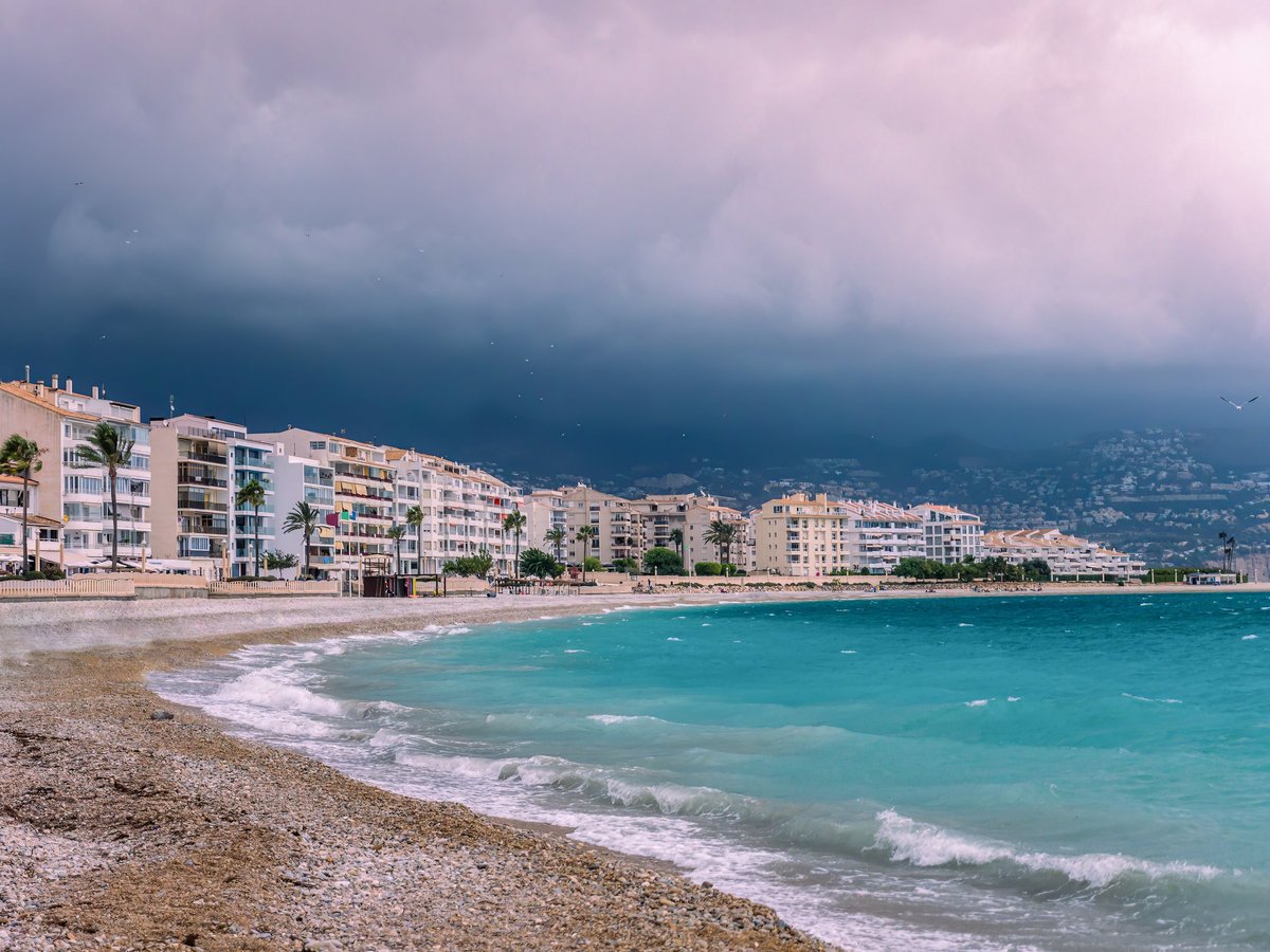 Coastal resort town with beachfront lined with modern buildings and palm trees