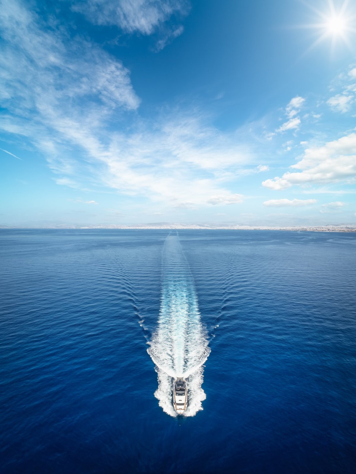 Aerial front view of a modern luxury yacht sailing over the ocean with high speed