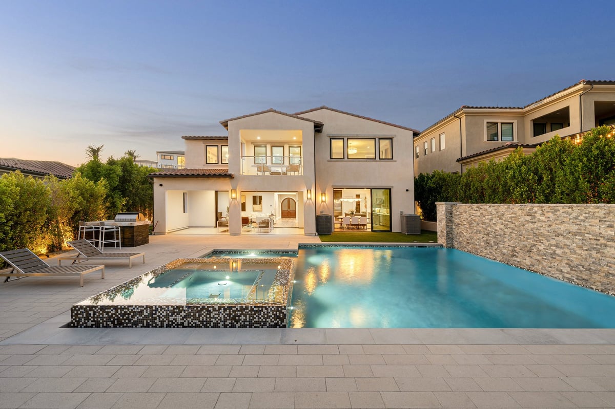 Luxurious modern house with a swimming pool and outdoor lounge area at dusk