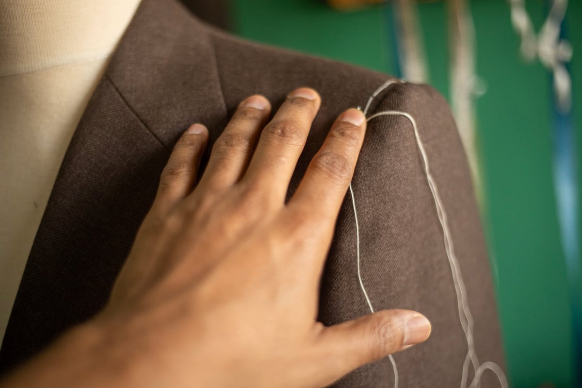 Close up of tailor hand stitching a sleeve to a bespoke jacket
