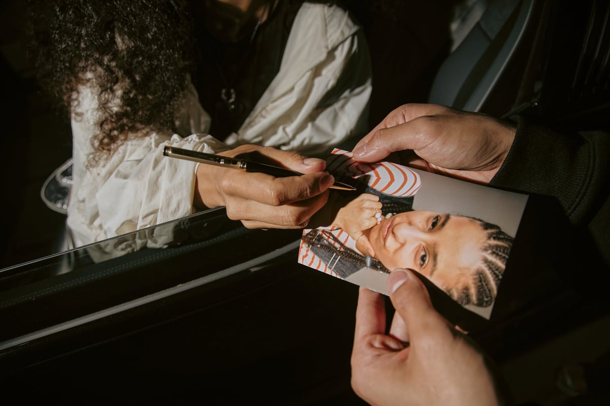 Famous singer signing photo for a fan in a car
