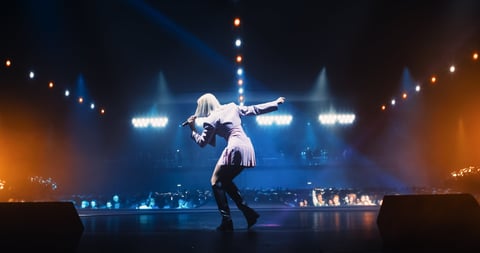 Pop artist performing on stage with sold out crowd