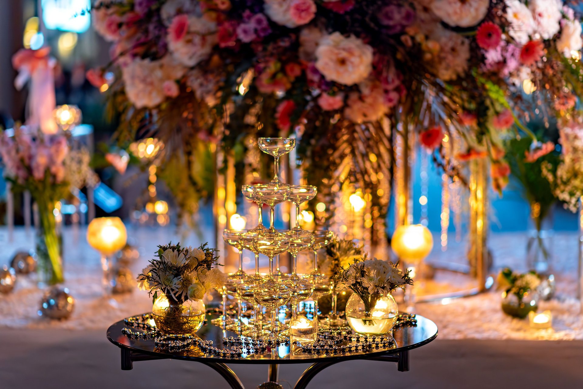 A Elegant wedding table setup with champagne tower, flowers, and warm lighting creating a romantic atmosphere