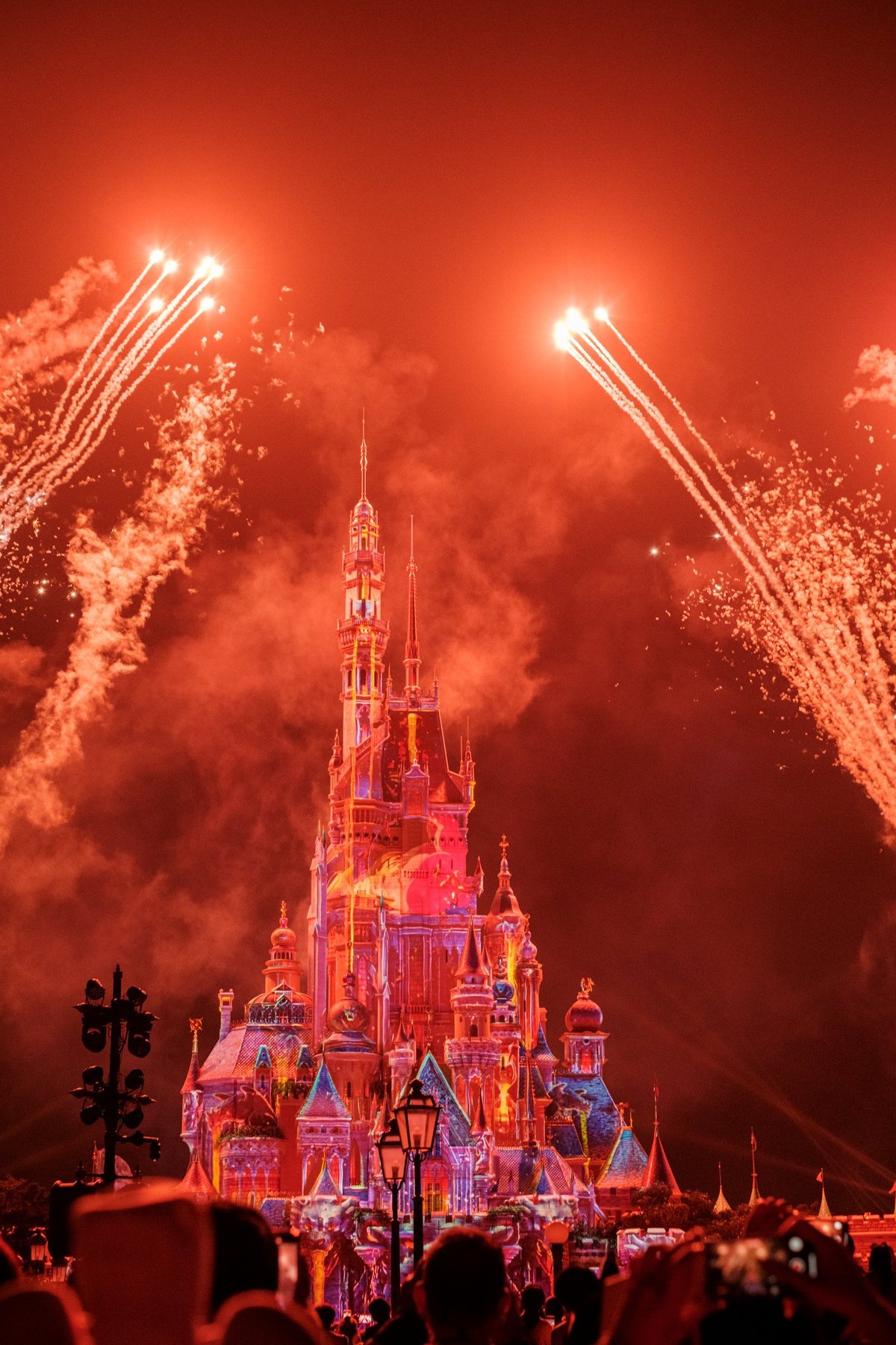 Colorful fireworks burst in the night sky, illuminating the majestic castle at Disneyland Hong Kong.