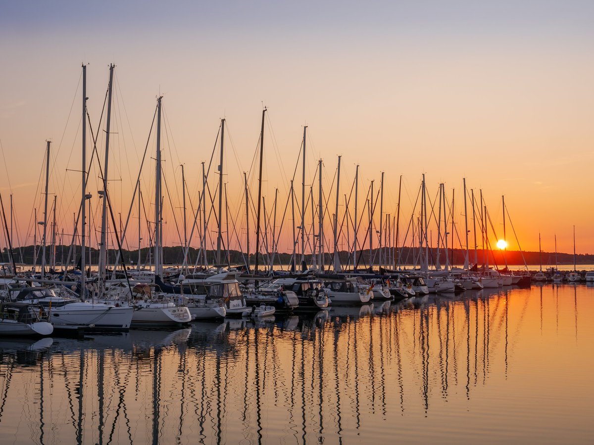 Row of sailboats moored in berths at Baltic Bay Marina, Laboe, Kiel Bay, Schleswig-Holstein, Germany at sunset