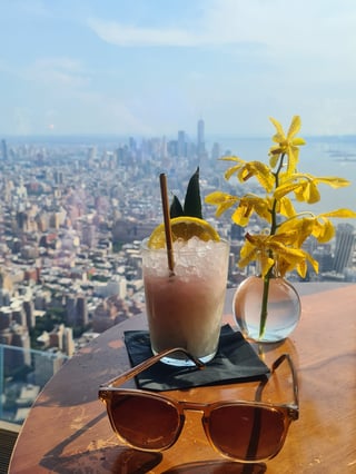 View from a high-rise rooftop bar overlooking city skyline at dusk