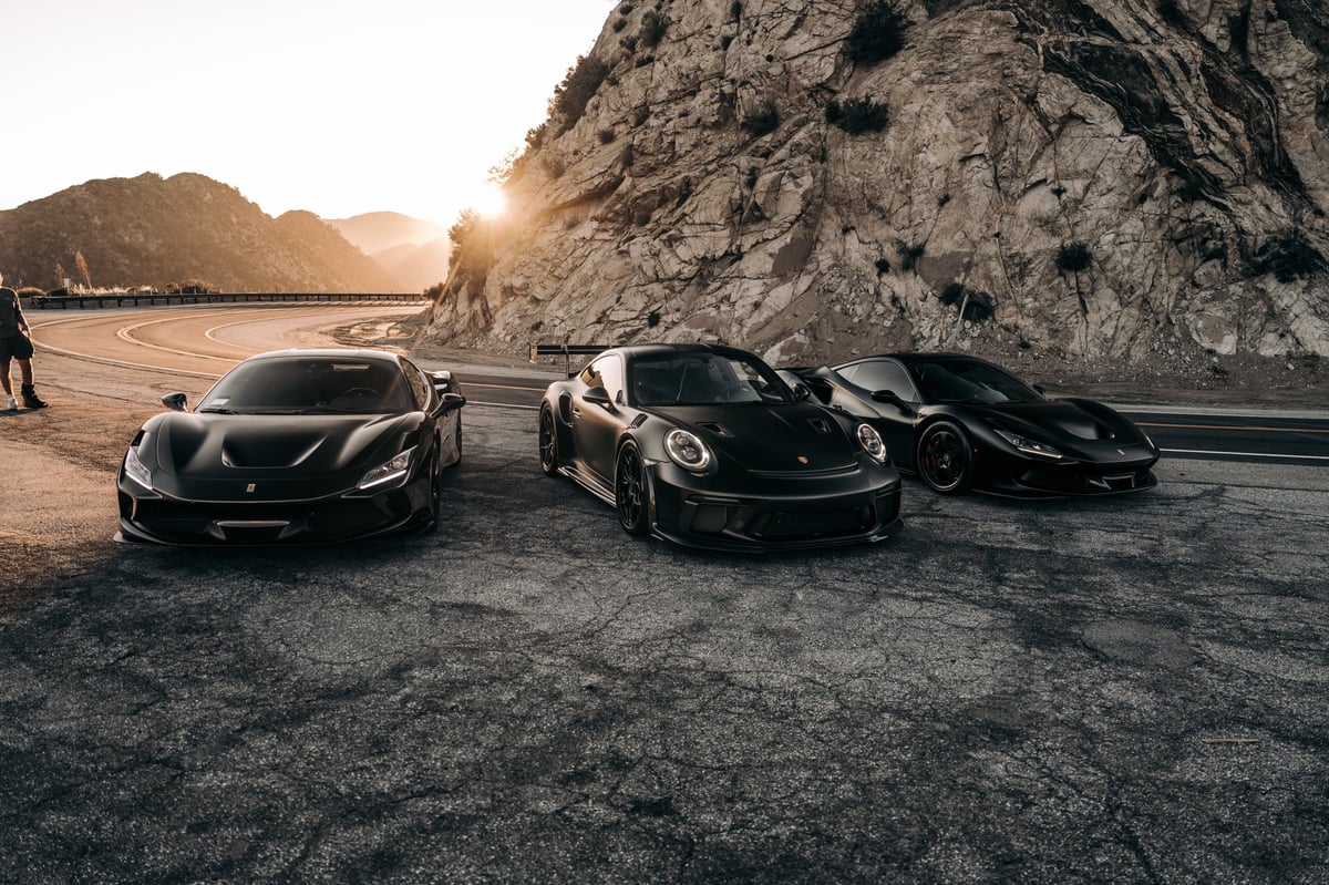 Ferrari F8s and a Porsche GT3 parked on the side of the road
