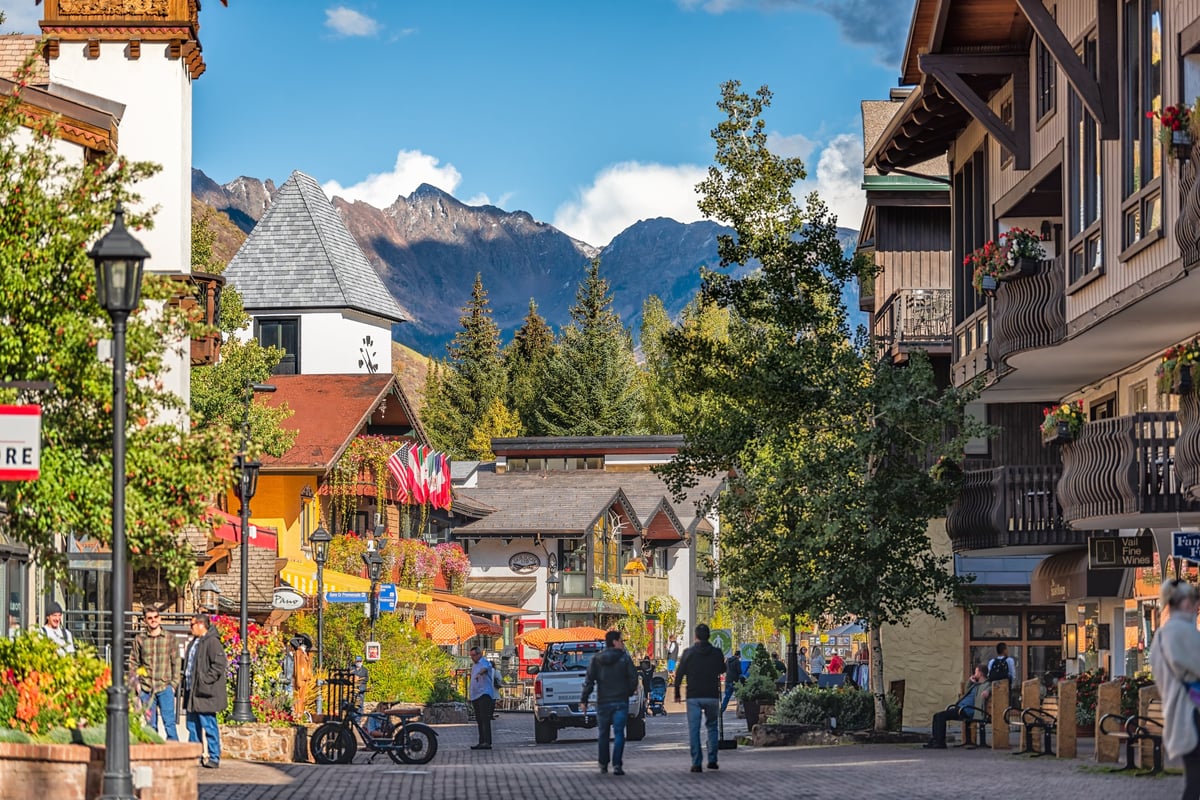 Colorado ski resort town with people, lodge hotel buildings in swiss architecture and mountain peak