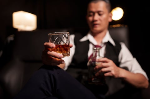 Gentleman holding a glass of whiskey in a sophisticated setting