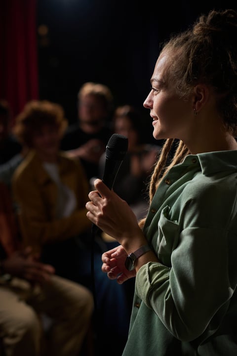 Woman holding a microphone while performing stand-up comedy on stage