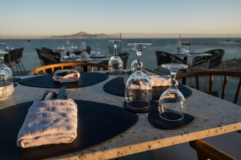 An inviting beachfront restaurant with beautifully arranged tables and a mesmerizing sunset over the ocean
