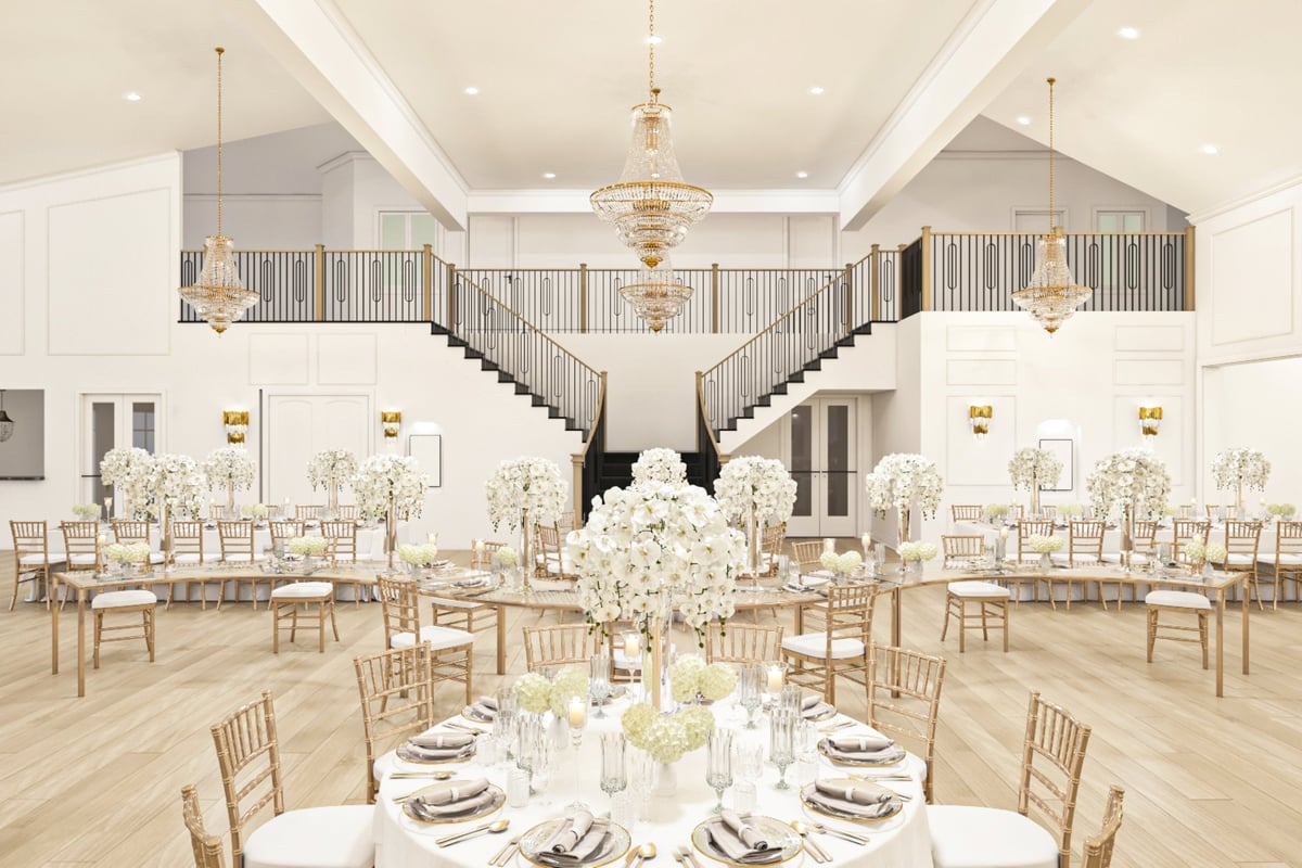 Extravagant ballroom setup featuring white floral decor, golden chairs, ornate chandeliers