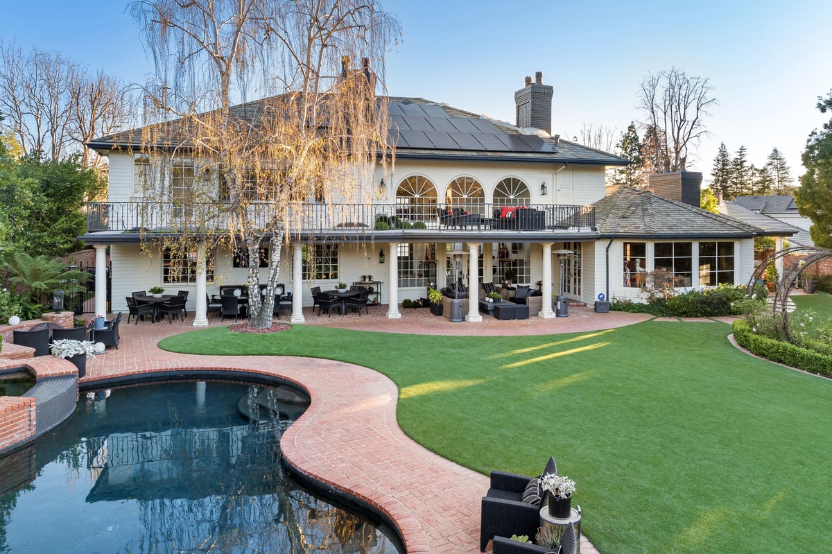 A luxury estate with a manicured lawn, swimming pool, grand entrance, and elegant architectural design