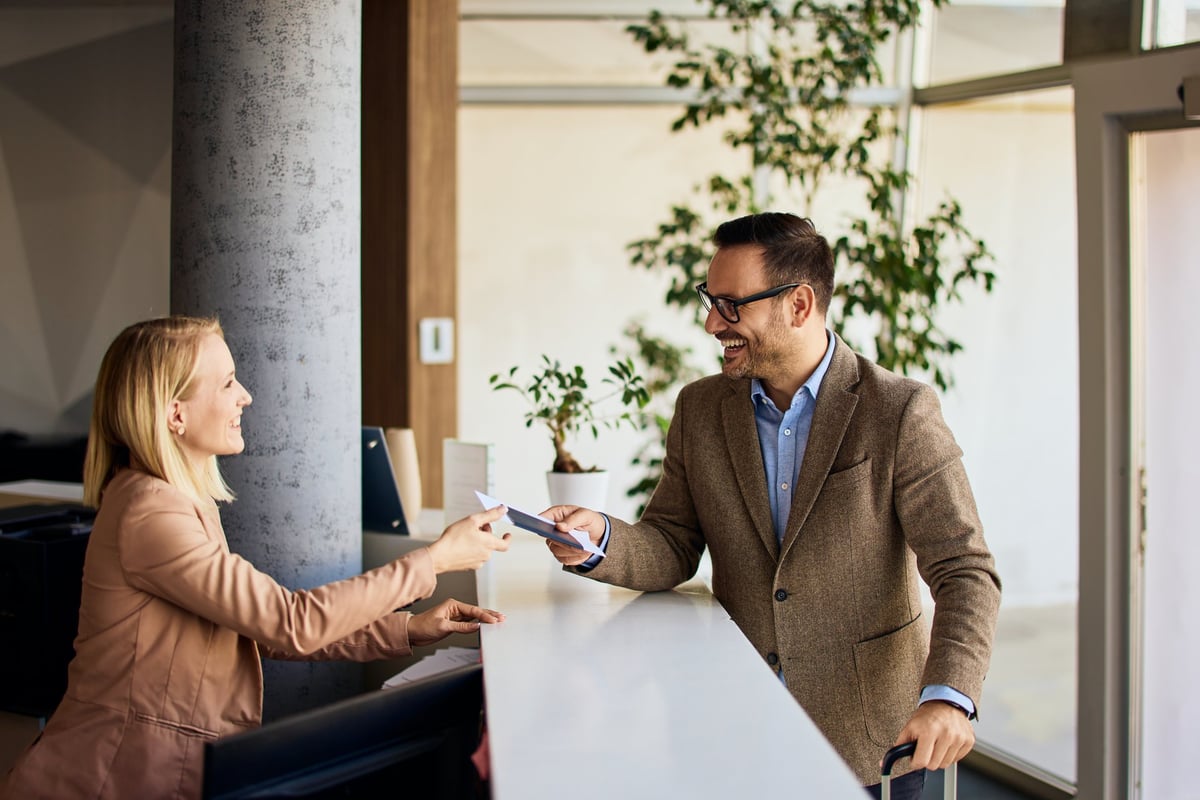 Businessman interacting with a receptionist while receiving a service at a reception desk