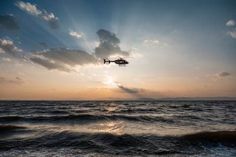 Helicopter flying over the sea at dusk