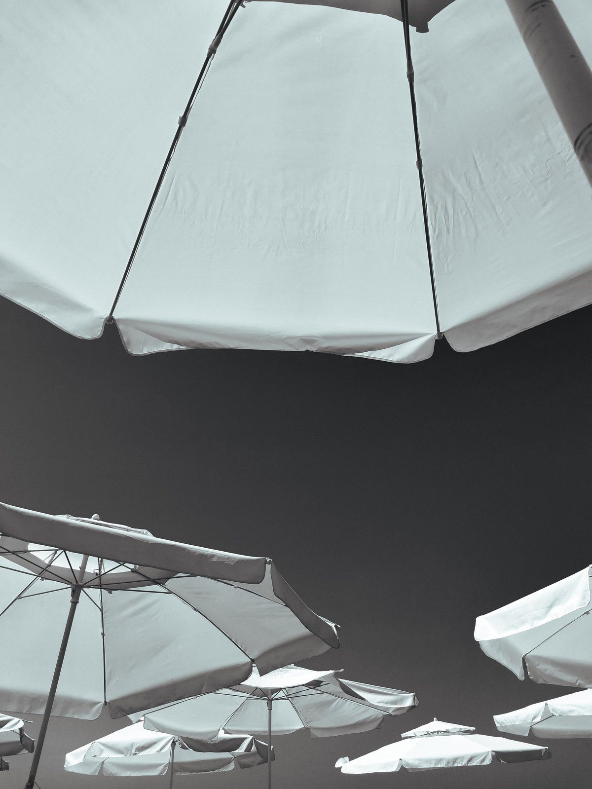 White beach umbrellas against dramatic sky on the French Riviera