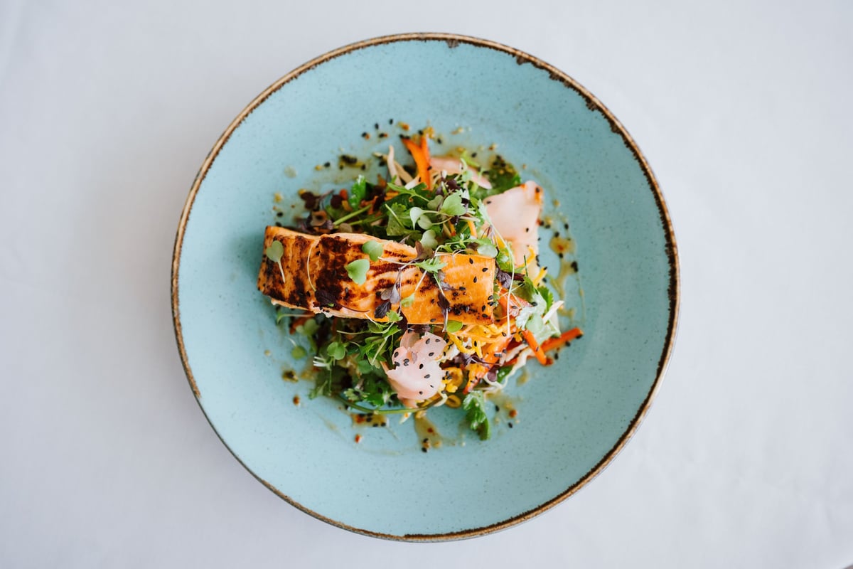 Grilled salmon with fresh greens on a blue plate