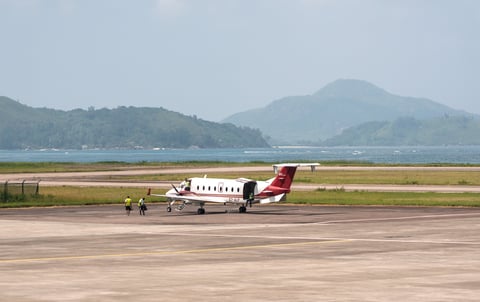 Small propeller airplane at Seychelles airport with ocean view