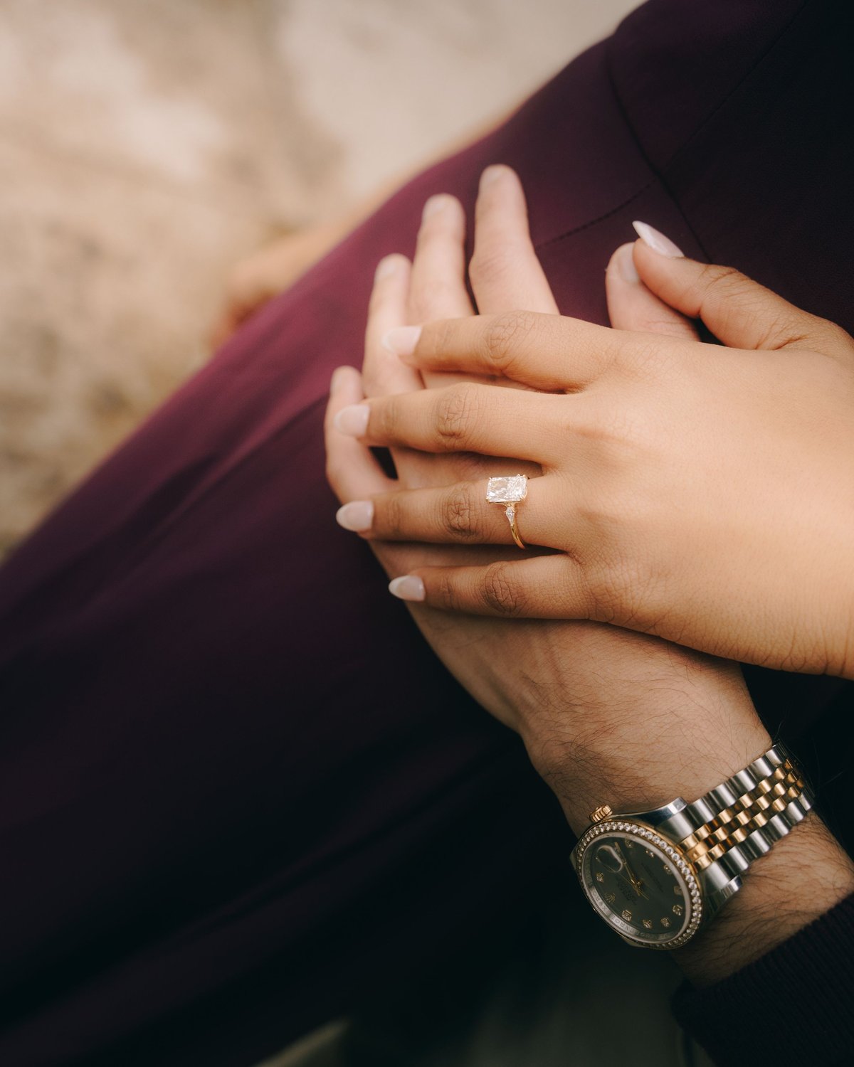 Close up of engagement ring on a woman's hand resting on her lap outdoors