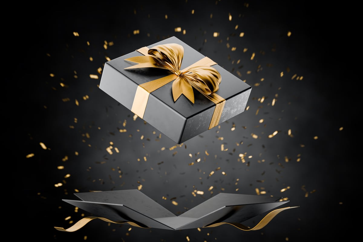 Open black gift box with golden ribbons symbolizing luxury and celebration