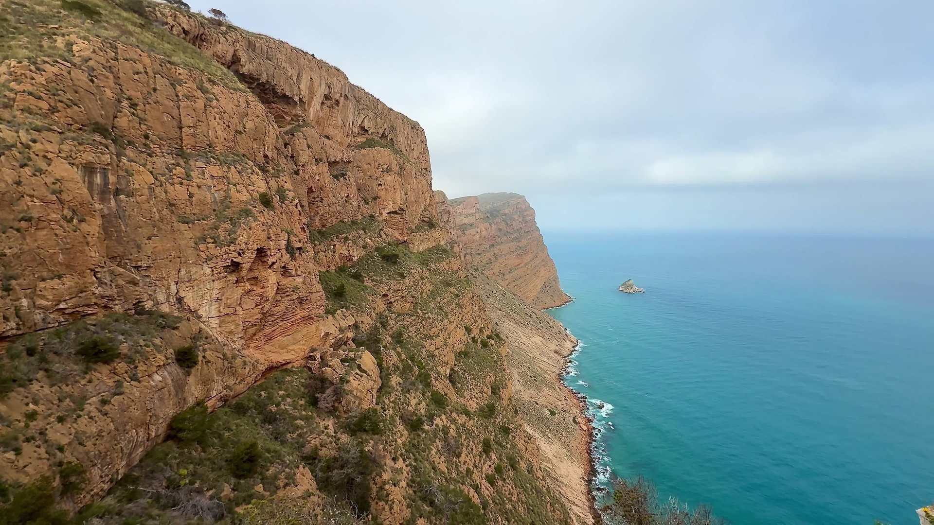 Experience breathtaking views of the rugged cliffs standing majestically beside a serene blue ocean on a cloudy day