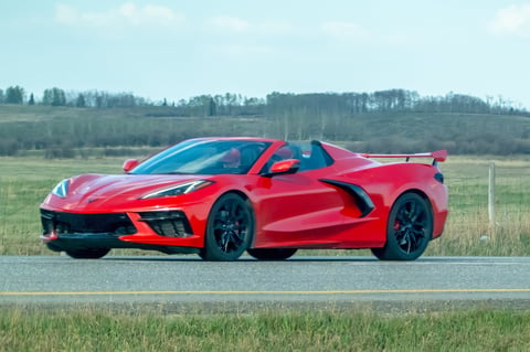 Red Chevrolet Corvette Stingray convertible speeding along a rural highway