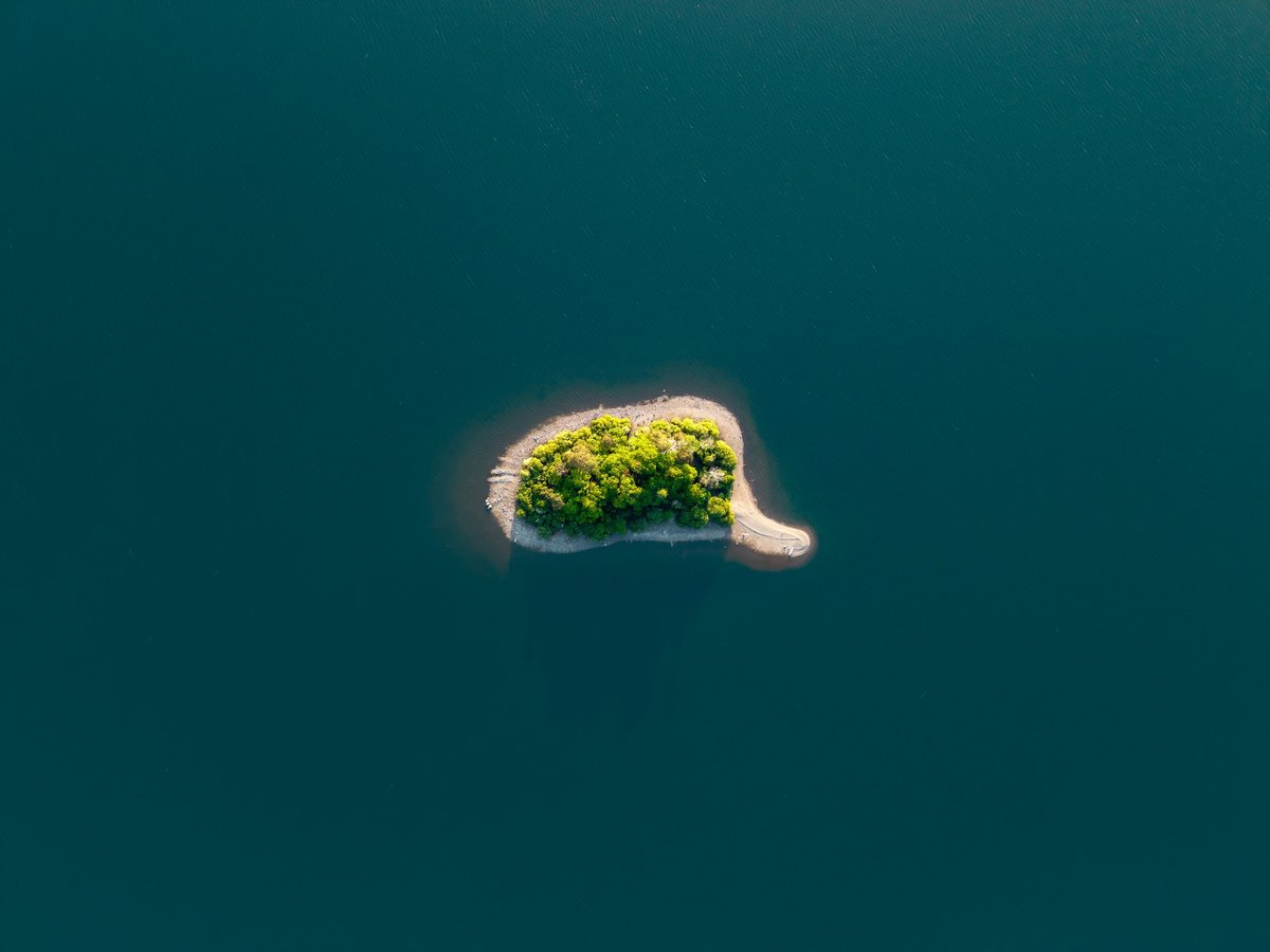 Aerial view directly above a small tropical island surrounded by calm turquoise Caribbean water