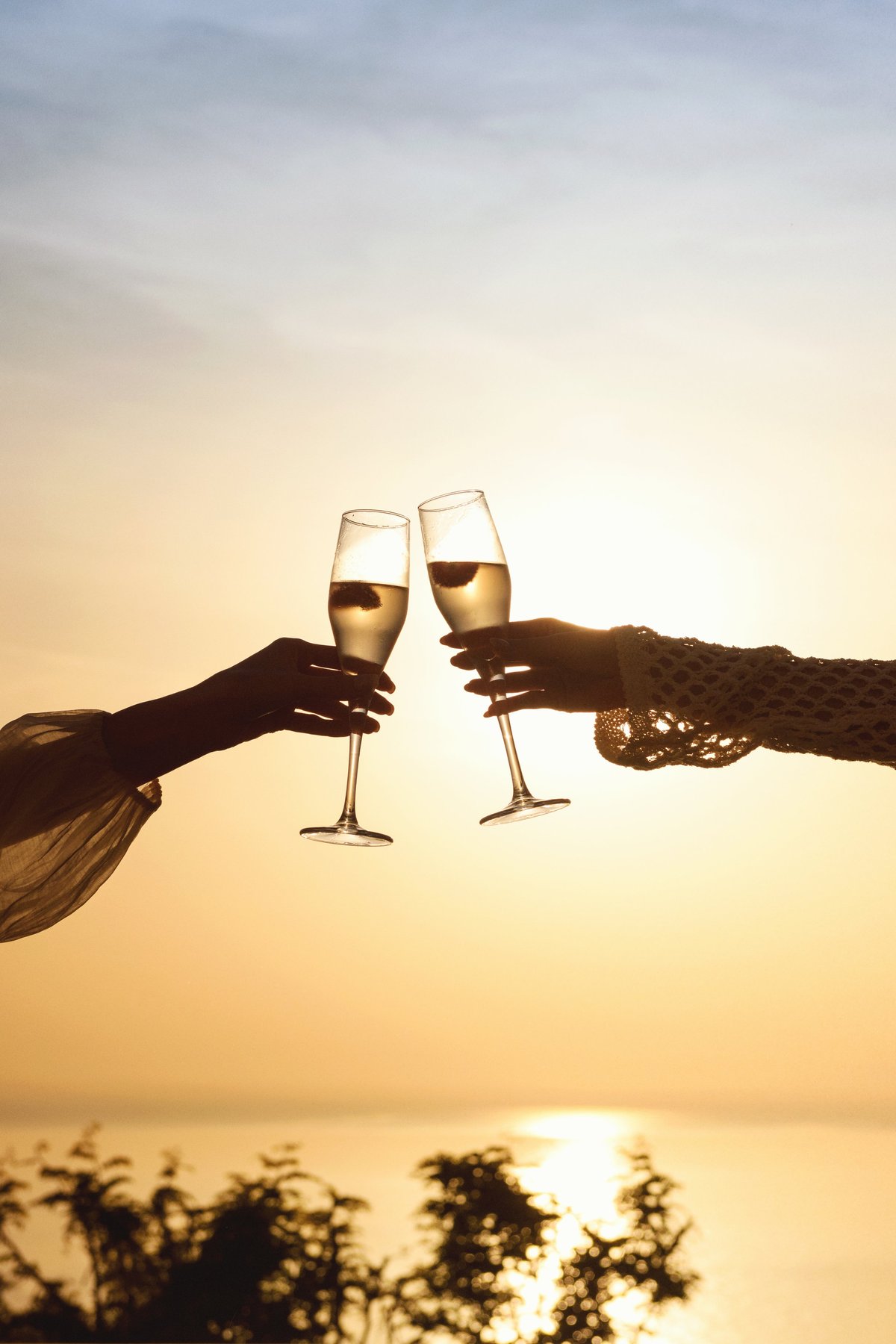 A romantic moment captured as champagne glasses clink together by the pool during golden sunset hour