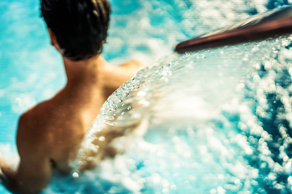 Muscular man relaxing in hydromassage treatment at spa resort