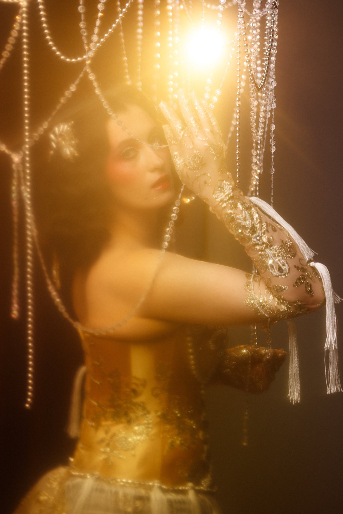Circus performer in golden vintage corset posing under chandelier