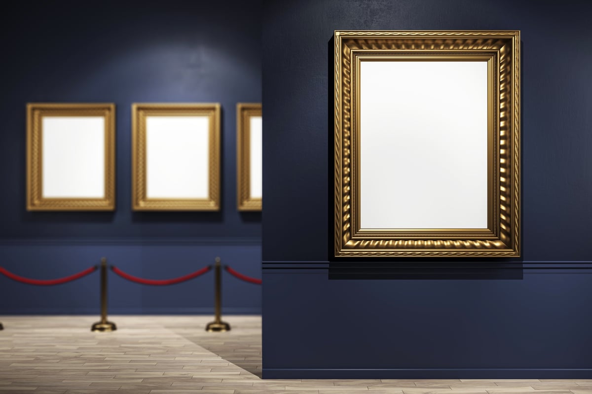 Elegant gold frames on navy walls in a museum hallway with red rope barriers
