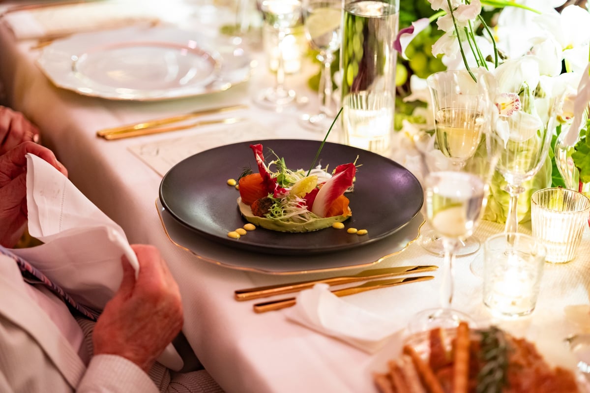 A beautifully plated appetizer served on a black plate during a formal candlelit dinner